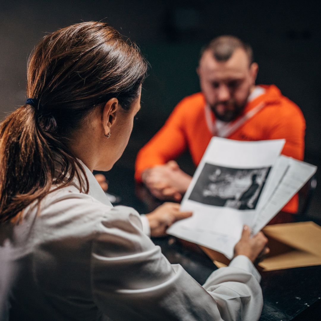 a lawyer meeting with someone in an orange jumpsuit
